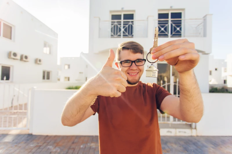 man holding key outside new home